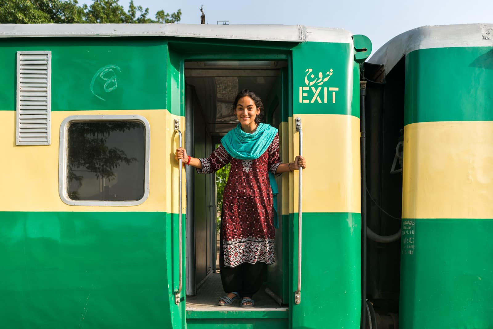 A girl hanging out of an open train door in Pakistan