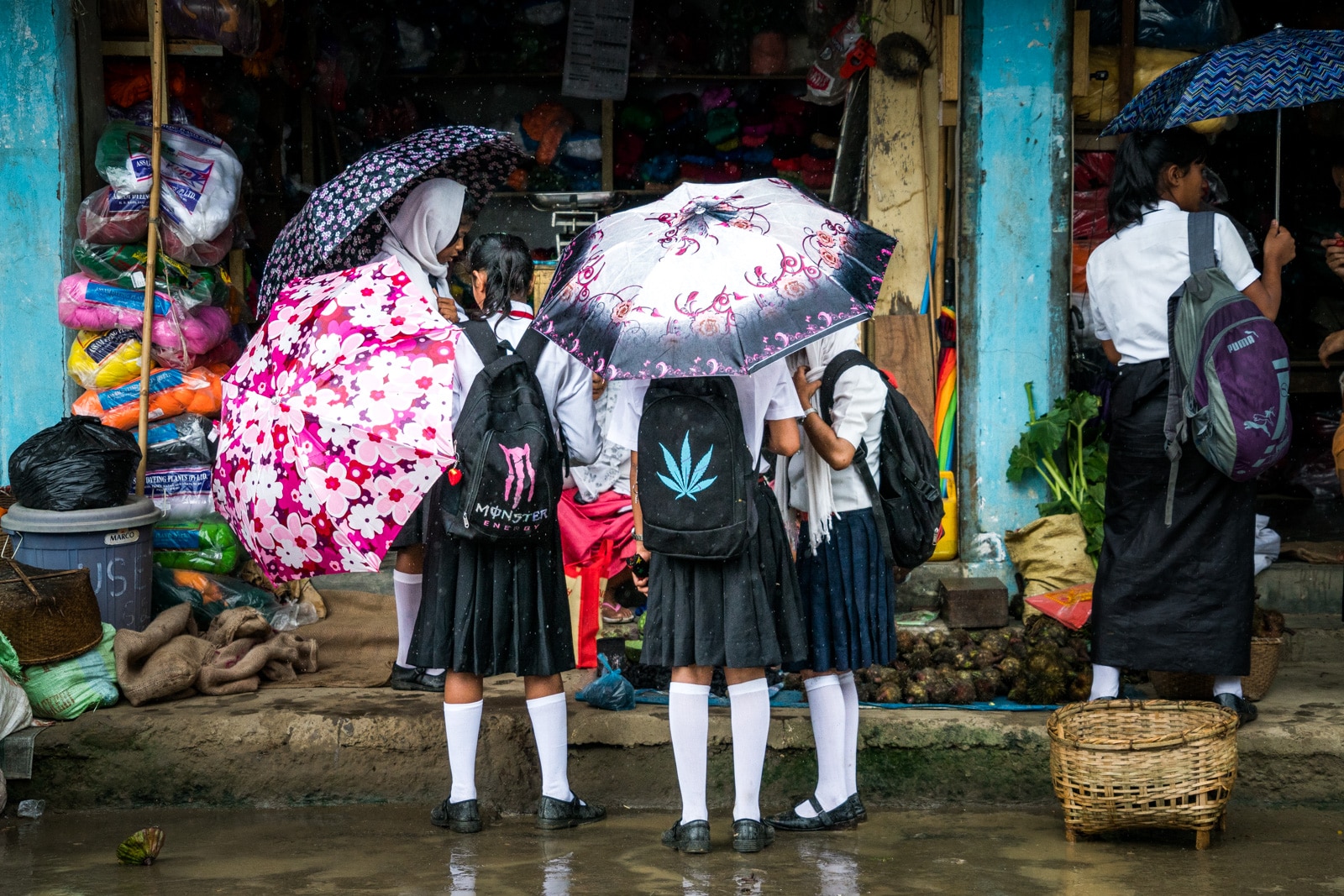 Monsoon travel packing list - Girls with umbrellas in Moirang, India - Lost With Purpose