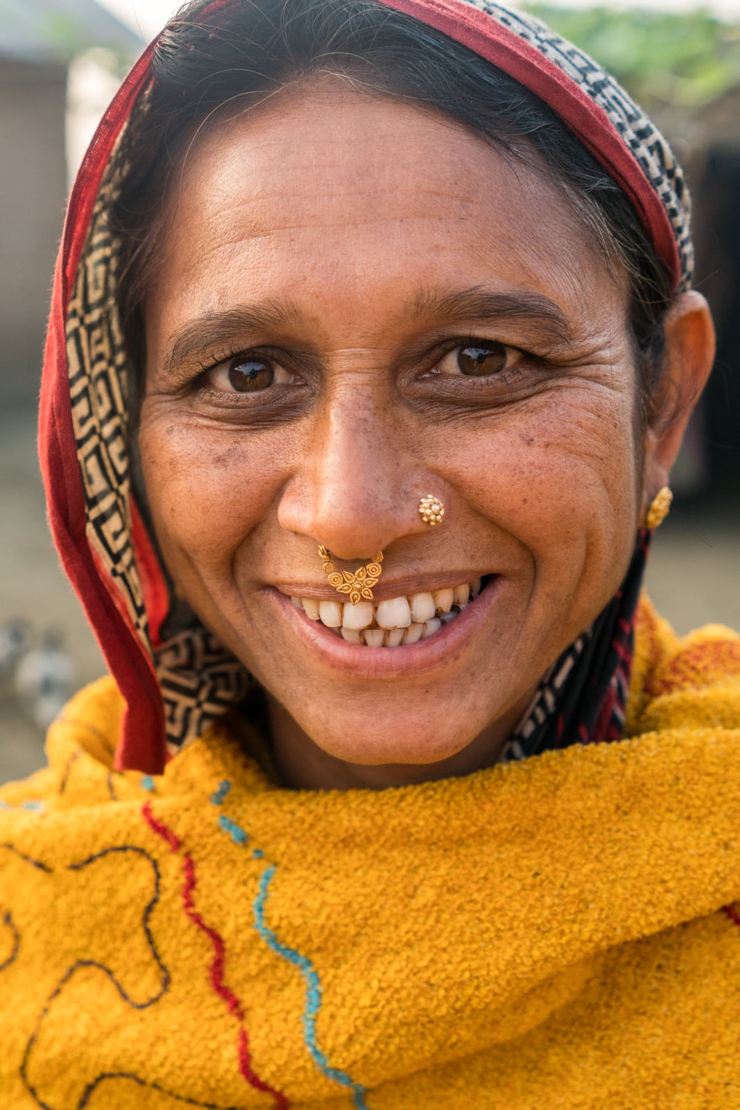 A smiling Bangladeshi woman in yellow headscarf in Assam, India.