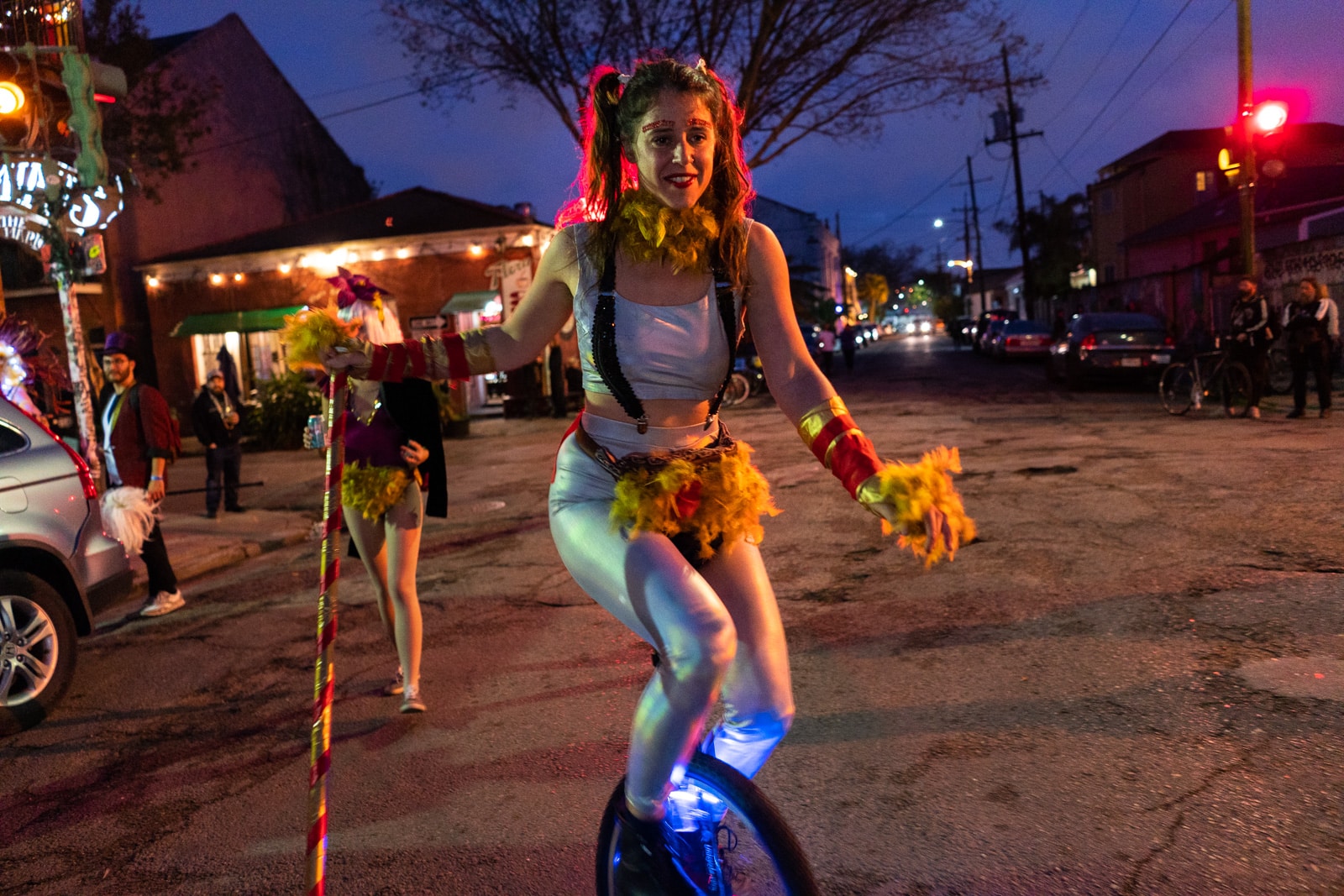 Girl riding a unicycle with a feathered fanny pack during Mardi Gras in New Orleans