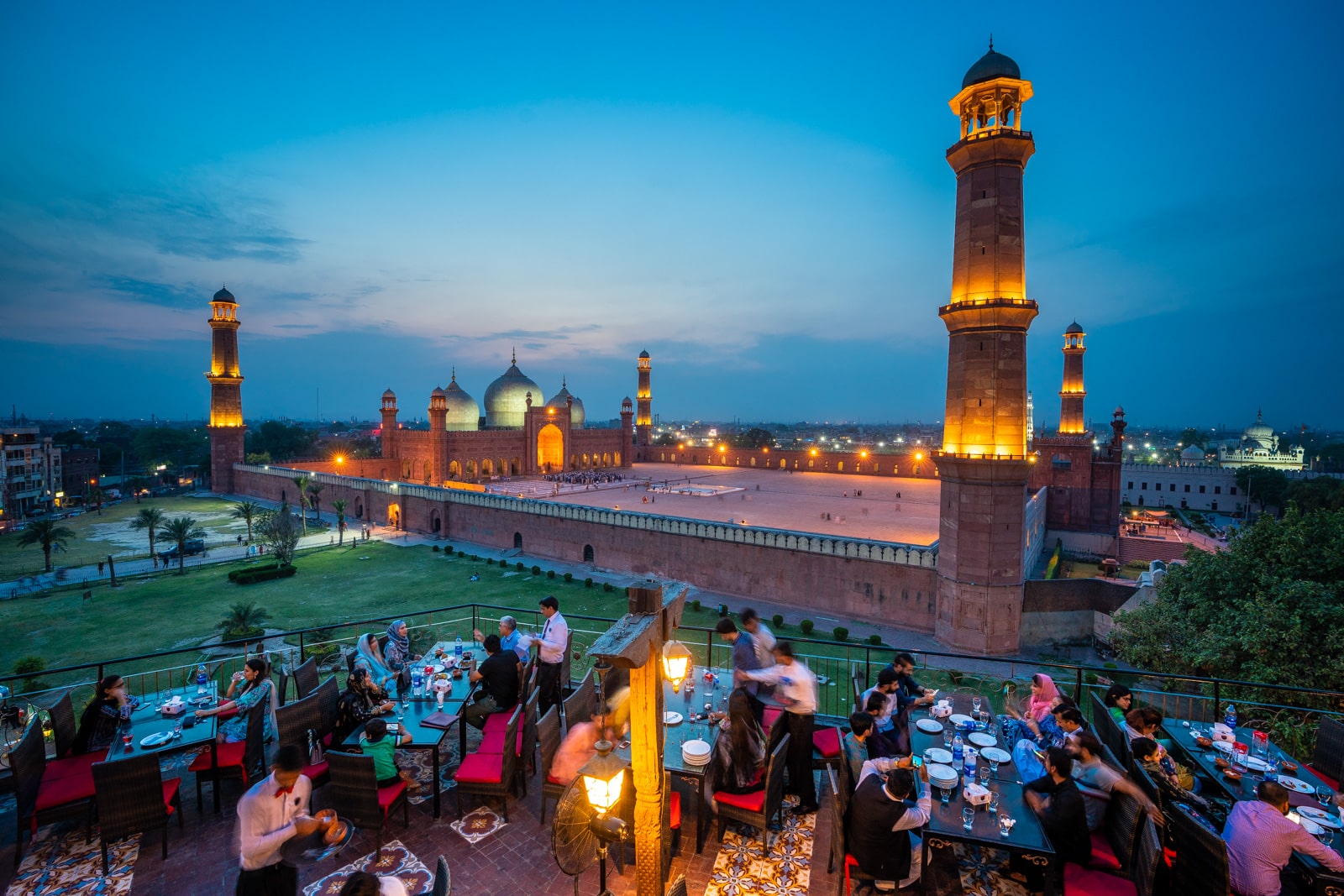 Badshahi Mosque in Lahore, Pakistan at sunset with people eating dinner a