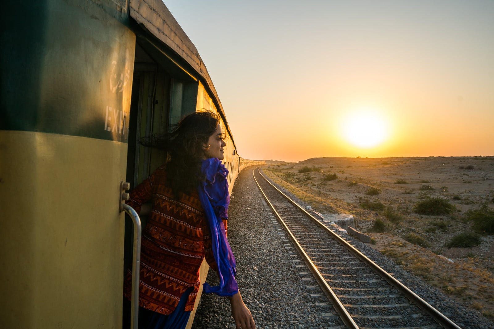 Female traveler riding a train from Lahore to Karachi, Sindh, Pakistan, at sunset