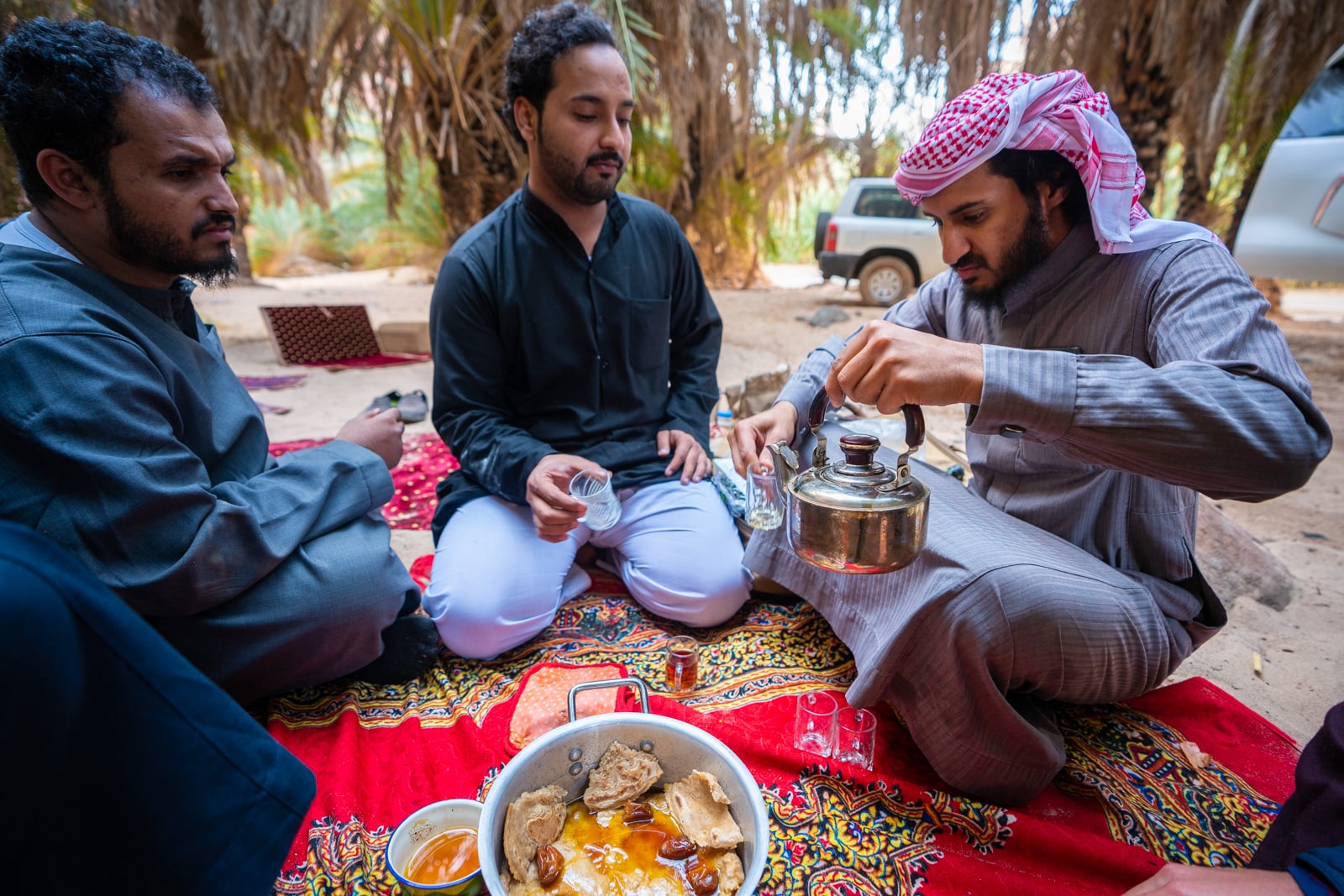 Saudi men eating on the ground while camping.